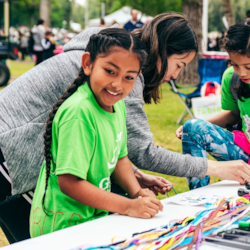 Girls on the Run participant smiles while working with a volunteer at a 5K event